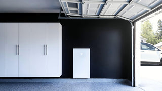 Tesla Powerwall 3 wall-mounted on black wall inside garage